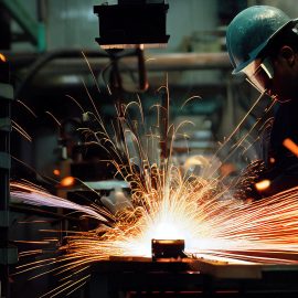 A welder wearing a protective mask and helmet captured in the process of welding